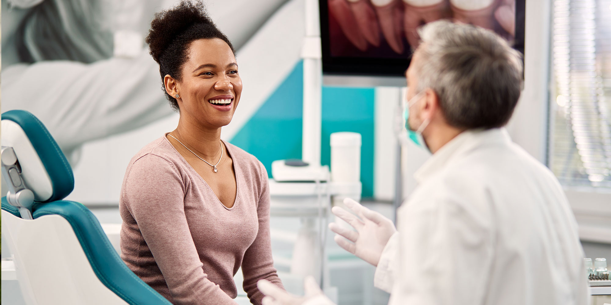 Happy Black woman talking to her dentist during appointment at dental clinic