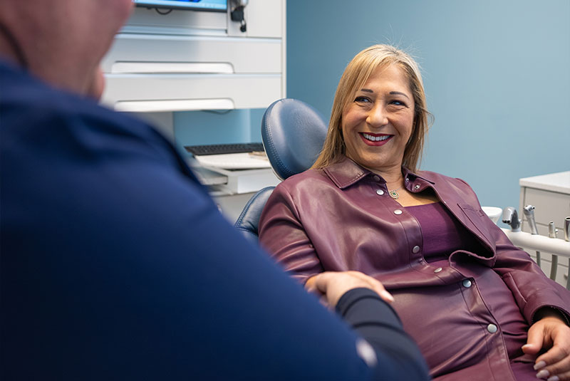 patient smiling brightly while talking to doctor about dental treatment