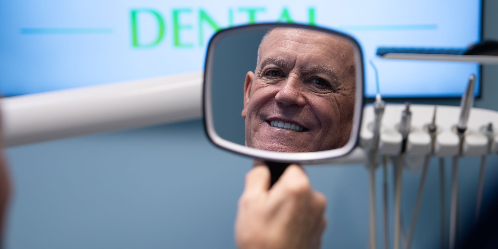 patient looking in the mirror after dental treatment smiling