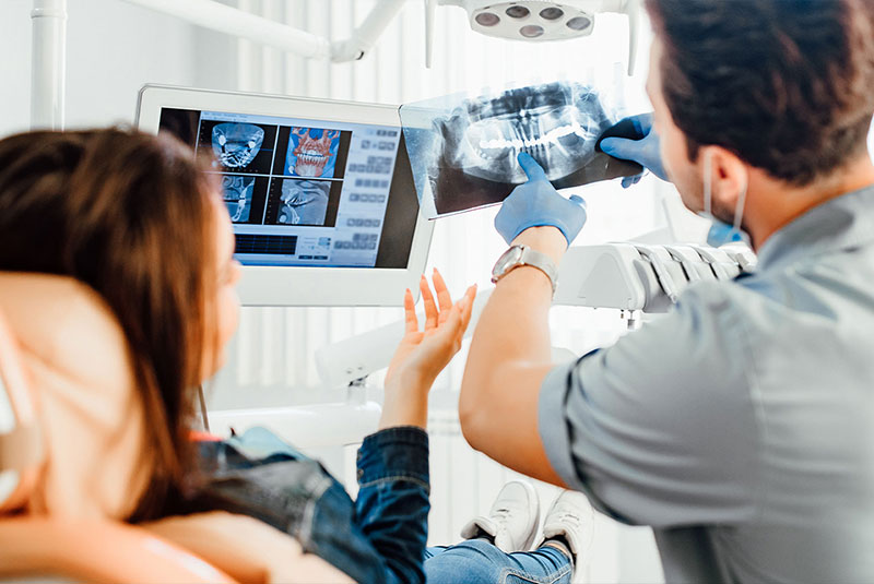 male dentist showing teeth x-ray to female patient at dental clinic