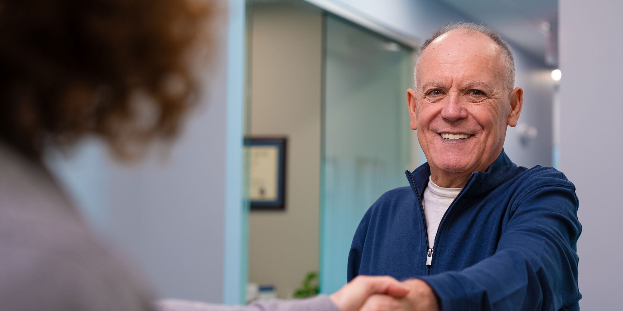 patient shaking hands with staff member at the front desk of the dental center