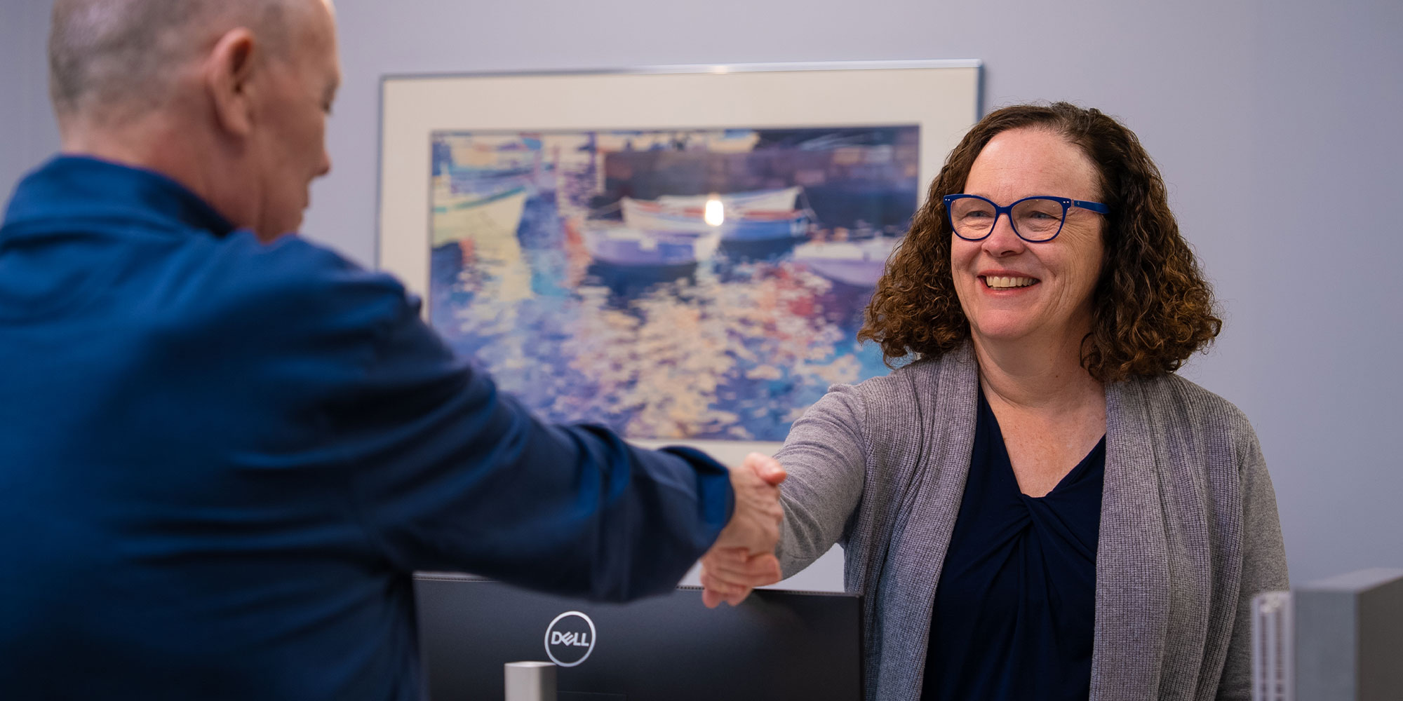 patient shaking hands with staff member at the front desk of the dental center